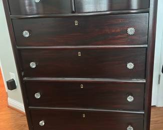 Dark Wood 6 Drawer Chest — Solid-looking dark wood five-drawer chest with serpentine front and decorative floral metal knobs. The piece features four large lower drawers and a pair of smaller top drawers, bracket feet, and inset keyhole escutcheons on each drawer front. Estimated dimensions and weight noted below make it a manageable bedroom piece for storage; perfect for clothing or linens. Good used condition with some surface wear and light scuffs consistent with normal use but no major structural damage.