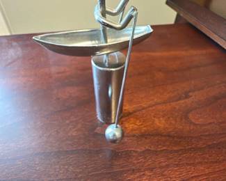 Modern Silver Metal Kayak Figurine — Stylish modern silver-tone metal desk figurine depicting a minimalist person paddling a kayak, perfect for office or shelf display. Solid-feeling metal construction with a boat-shaped hull, stylized stick-figure paddler, and mounted base that allows the piece to stand upright. Measures approximately 7 inches tall overall and is lightweight and easy to place on a desk or bookcase. Good condition with light surface wear and minor scuffs consistent with normal use.