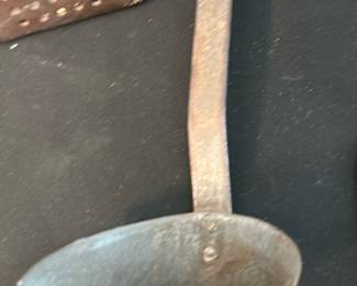 Iron Fireplace Ladle — Heavy forged iron fireplace ladle with a long flattened handle and a deep round bowl; appears hand-forged with surface rust and patina consistent with age. Useful as a hearth or blacksmithing tool or as rustic decor; pairs with the three-prong fireplace fork shown. Solid construction but shows surface corrosion and wear from use. Overall length approximately 20–24 inches and offered as-is.