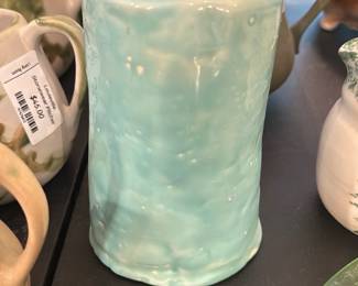 seafoam green ceramic vase — Seafoam green hand-formed ceramic vase with a slightly irregular, wavy rim and glossy glaze. The piece appears wheel- or hand-built with subtle texture and glaze pooling; interior shows some dark speckling or kiln residue near the base. Good overall condition with normal firing marks and no obvious large chips or cracks visible in photos. Compact size works well for a small bouquet or as an accent on a shelf or table.