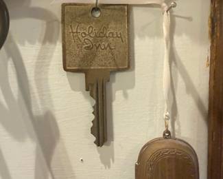 Holiday Inn Brass Hotel Key — Large brass hotel key fob stamped "Holiday Inn" on the rectangular head with an attached vintage-style key. The piece is decorative and likely a promotional or oversized display key rather than a working modern key; patina and surface wear are visible consistent with age. Good solid metal construction with attractive aged brass finish; ideal for display, hotel or motel collector, or signage decor. Measures approx. 7.5 inches tall overall and shows light scratches and tarnish but no major damage.
