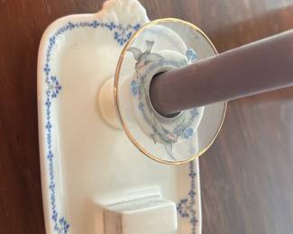 vintage Haviland Limoges porcelain — Delicate porcelain wall sconce featuring a rectangular backplate with scalloped shell accents and a blue floral garland border. The socket collar has hand-painted blue flowers and gilt rim; currently shown with a brown candle-style bulb insert (not original). Good vintage condition with minor surface wear and light crazing consistent with age; no obvious chips or cracks visible in photos. A decorative piece suited for cottage or traditional dining-room lighting where a small wired or hardwired restoration is acceptable.