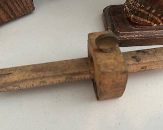 wooden marking gauge — Small wooden marking gauge used for woodworking layout; measures and scores parallel lines using the adjustable sliding beam and locking thumb screw. Handtool shows heavy surface wear, darkened patina and some residue from use but appears structurally intact with the metal pin present. Compact and classic in form — useful as a display piece for tool collectors or for light shop use after cleaning. Approximately pocket-sized based on photos; seller notes say item was photographed in the sun room.