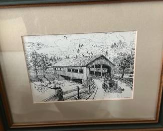 Framed Covered Bridge Ink Print — Framed black-and-white ink print depicting a rural covered bridge with an antique automobile in the foreground. The piece is double-matted and set in a wood frame with green accent molding; paper image shows detailed pen-and-ink linework. Overall framed piece is medium wall art suitable for entryway or hallway display; measurements given are approximate. Frame and mat show light surface wear and sun-fading at edges but the print itself appears intact with no visible tears or stains.