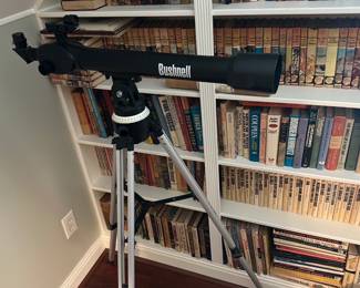 Bushnell Telescope — Bushnell-branded refractor telescope on an adjustable aluminum tripod shown in photos. The scope tube is matte black with white Bushnell lettering and includes a simple sighting scope and pan/tilt mount with degree markings. Good cosmetic condition with minor scuffs visible on the tube; tripod legs and mount appear functional. Ideal as an entry-level telescope for casual stargazing or daytime viewing; measures compactly on its included tripod.