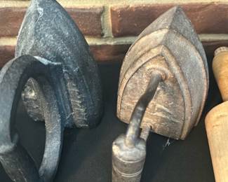 Cast Iron Sad Irons — Group of three small cast-iron sad irons shown together, classic wedge-shaped solid irons used before electric models. Heavy solid construction with loop handles (one detachable/hinged style visible) and surface rust/patina consistent with age; one has a short curved handle stem. Good estate-condition as decorative pieces or for restoration—no visible makers' marks in photos. Each iron is small and heavy; suitable for display or repurposing in a vintage kitchen or collector grouping.