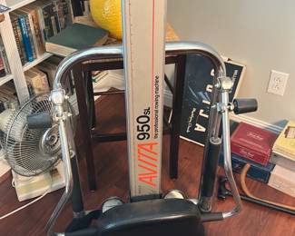 Aviva 950 SL Rowing Machine — Aviva 950 SL professional rowing machine with tall central rail and padded seat shown in photos. The column is marked "Aviva 950 SL" and "Made in USA"; frame is chrome with black plastic/rubber grips and a cushioned seat. Sturdy home-gym cardio rower suitable for low-impact full-body workouts; unit shows light surface wear consistent with normal use but appears complete with handles and foot supports. Measures roughly as listed below; sold as-is with no service history provided.