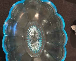 Blue Rimmed Glass Serving Bowl — Attractive scalloped glass serving bowl with a bright blue rim and a pressed starburst medallion in the center. The bowl is molded with petal-like segments around the sides and a smooth interior; it appears to be mid-century style pressed glass suitable for serving or display. Condition is good with light surface scratches visible from use but no obvious chips or cracks in the photos. Approximately medium sized and lightweight for easy handling.