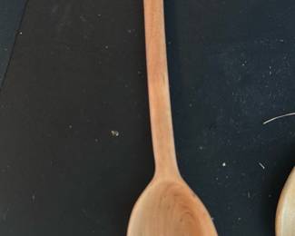 Handmade Wooden Spoon — Long, handmade wooden spoon with a smooth carved bowl and round handle; a small wooden tag tied to the handle reads "THANKS CHARLES & MARY". Appears to be a simple kitchen utensil or decorative piece carved from a single piece of light hardwood with visible grain. Light surface wear and small marks consistent with gentle use; no cracks or major damage visible. Measures like a stirring/server spoon suitable for kitchen use or display.