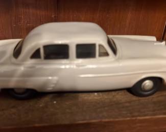 Gray Toy Sedan — Small white diecast toy sedan with sealed body and metal chassis; photos show a four-door classic-style car with metal bumpers and rubber tires. Underside shows wear and surface rust on the metal base and axle areas; body paint is intact with light scuffs consistent with age and play. Compact shelf/display piece roughly the size of typical 1:43–1:64 scale models; good condition for display with noted underside corrosion. No visible maker stamps or readable text on the photos.