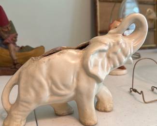 MCM Ceramic Elephant Planter — Cream ceramic elephant planter with trunk-up detail and glazed finish. Hollow body with an oval planting cavity shows kiln-staining and crazing inside; base is unmarked and shows age-related wear to feet. Decorative yet functional for small succulents or as a shelf accent; neutral cream color and simple sculptural form suit traditional or cottage decor. Good structural condition with surface wear and discoloration consistent with age and use.