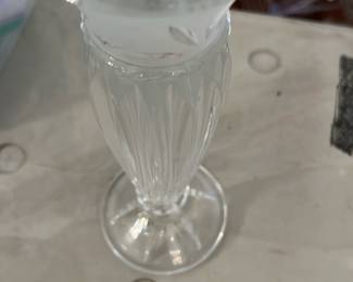 Cut Crystal Bud Vase — Tall clear cut crystal bud vase with an etched starburst motif at the flared rim and vertical fluted cutting along the body. The vase stands slender with a round foot and displays crisp cuts that catch the light; no visible chips or cracks in photos. A classic decorative piece for a mantel or small floral arrangements, showing light surface wear consistent with gentle use.