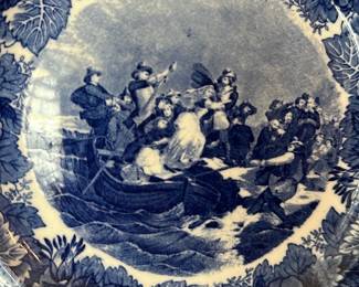 Wedgwood Blue Transfer Plate — This Wedgwood blue transferware plate titled 'Landing of the Pilgrims Plymouth' highlights classic English ceramic design and historic imagery. The porcelain plate features a central nautical scene surrounded by a floral border in deep blue on white and is marked on the back with 'Landing of the Pilgrims Plymouth', Wedgwood Etruria England and a copyright date of 1898. Plate is ideal for wall display in a living room and measures approximately the size of a decorative dinner plate. Overall condition is good with surface crazing consistent with age and minor wear visible on the reverse; hanger shown is not original.