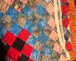 Handmade Patchwork Quilt — Hand-sewn patchwork quilt made from assorted cotton prints and plaids in a classic nine-patch style. The quilt shows mixed small floral, paisley, gingham and novelty cotton squares with a solid-color binding; photos show typical light wear and some puckering from use but no major tears visible. Good choice as a cozy throw or decorative bed-layer; measures approximately as shown below and is lightweight and foldable for easy handling.