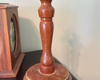 Wooden Display Stand — Solid turned-wood hat or wig display stand with a classic baluster column and round stepped base. The stand shows surface wear and scuffs on the base and finish loss consistent with age and use but remains sturdy for display; top has a small metal hanger insert. Good for retail merchandising, sewing rooms, or decorative display of hats and wigs. Measures compactly and is easy to move; see dimensions for sizing.