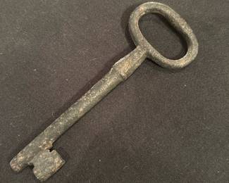 Iron Skeleton Key — Large iron skeleton key with an oval bow and long shaft; the bit shows simple warding typical of older utility or furniture keys. Solid, heavy-feeling metal with surface corrosion and verdigris consistent with age and long storage — no visible maker's marks. Good decorative or collectible condition as a rustic display piece; measurements and weight are estimated from photos.