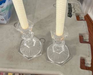 Pair Clear Glass Candlesticks — Pair of clear glass candlesticks with hexagonal stepped bases and simple column stems, shown fitted with rolled beeswax-style taper candles. Clean, transparent glass with classic understated lines suitable for dining or mantel display. Minor surface dust and light handling marks visible in photos but no obvious chips or cracks. Each stands approximately 8–9 inches tall and they make an easy everyday accent for table settings or seasonal decor.