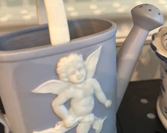 Wedgwood Style Jasperware Watering Can — Light blue jasperware-style ceramic watering can with applied white relief cherub decoration and a removable spout/rose. The piece echoes Wedgwood neoclassical jasperware styling with matte-blue body and white bas-relief figures; good decorative condition with minor surface wear visible in photos but no obvious chips or large cracks. A decorative, small tabletop or indoor plant watering piece measuring compactly to fit a shelf or planter area.