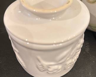 Butter Ball Covered Ceramic Baker — Small white covered ceramic baker marked "Butter Ball" on the base. Molded floral/fruit relief around the exterior and a fitted lid; collectible kitchenware produced for Butter Ball (mark visible). Shows light staining on the rim and base consistent with kitchen use but no visible cracks or chips. Handy for serving or collecting as part of a branded kitchen ware set; compact size makes it easy to display or store.