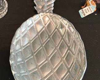 Pewter Pineapple Dish — Decorative pineapple-shaped metal bowl with a textured lattice interior and a stylized leaf top. Solid-feeling cast construction with four small molded feet on the base; ideal as a catchall or table accent. Shows light surface wear and scuffing consistent with previous use but no cracks or breaks visible in photos. Measures a medium tabletop size and pairs well with coastal or tropical-themed decor.