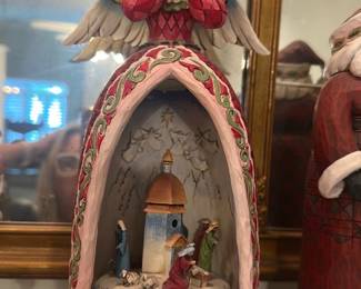 Silent Night Angel Nativity — Painted resin nativity scene topped with a praying angel and halo, sculpted in a domed chapel motif with hand-painted floral trim and the words "Silent Night" on the base. Interior shows a small manger scene with Mary, Joseph, baby Jesus and animals beneath a painted star/leaf motif; colors are soft pastels with gold accents. Likely decorative holiday figure suitable for mantel or shelf display; overall good cosmetic condition with no visible chips or repairs in photos. Measures small-to-medium tabletop size and pairs well with other seasonal decorations.