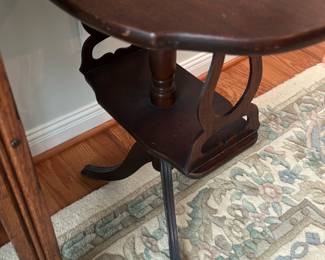 Mahogany Oval Accent Table — Small mahogany-finished oval accent table ideal for a living room corner or beside seating. It features a turned central column, lyre-style pierced side supports and a lower shelf for display; the top shows light surface wear and there is minor finish loss at the feet. Overall compact and handy for lamps or decorative objects; measurements are approximate and intended for estate-sale listing. In fair condition with visible scuffs and chip at one foot but structurally sound.