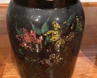 Black Glazed Ceramic Jar w lid — A black glazed ceramic ginger jar with hand-painted floral decoration around the body and a fitted lid. The jar shows surface wear and paint loss on the rim and small chips at the lip, plus crazing consistent with age; otherwise structurally intact. Sturdy, decorative piece suitable for display on a shelf or mantle; pictured measurements are estimates derived from visual scale. No maker's marks visible in photos.