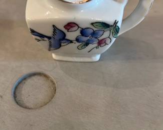 Made in Japan Small Porcelain Creamer — Small porcelain creamer marked "MADE IN JAPAN" on the base with hand-painted blue bird and floral decoration and gold trim on the lip. Compact, square-bodied cream pitcher with integrated handle and flared spout; appears to be mid-20th century export ware. Condition is good overall with light surface wear and small discoloration on the rim shown in photos; no obvious chips or large cracks visible. Ideal for collectors of Japanese export ceramics or for decorative tabletop use.