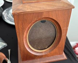 Walnut  & Brass Photo Carousel — Small walnut wooden photo carousel with brass ring top and four oval glass windows for rotating pictures. A gold sticker reads "Genuine American WALNUT" on the side; piece shows light surface wear and a small scratch but is structurally sound. Compact tabletop size makes it suitable for a mantel or desk; photos stored inside as shown are included but may need repositioning. Classic mid-century styling with warm walnut grain and brass trim gives it decorative appeal.