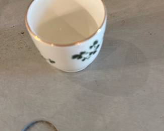 Carrigaline Pottery Cork Ireland Cup — Small porcelain cup stamped on the base "CARRIGALINE pottery Co Ltd CORK IRELAND" with a simple shamrock/leaf motif and gilt rim. The piece is light-weight, likely decorative or for small servings/espresso; Carrigaline was a Cork, Ireland pottery known for cottage-style domestic wares. Glaze shows fine crazing consistent with age and there is light wear to the gold rim but no chips visible in photos. Measures small and would be a nice addition for collectors of Irish pottery or for display.