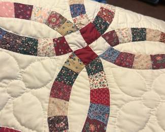 Handmade Double Wedding Ring Quilt — Hand-sewn double wedding ring quilt with multi-floral patchwork rings on a cream ground and a deep red binding. The pattern and piecing suggest traditional handwork; quilting is in a flowing stipple/loop style. Seller notes list this piece in the bonus room with a blue price tag; overall condition appears good with normal light wear from use and no obvious stains or large damage visible in photos. A classic bedcover suitable for a twin or layered throw depending on exact size.