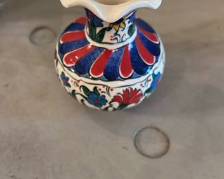 Ephesus Ceramic Vase — Hand-painted Ephesus ceramic vase with a flared ruffled rim and traditional floral motifs in red, blue and green. The base is marked "Ephesus Ceramic" with additional hand-painted numbers/letters; decorative glazing is intact and colors are bright. Small tabletop accent measuring a few inches tall, showing only light surface wear consistent with display use. Good decorative piece for a shelf or small grouping.