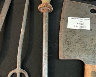 Wood-Handled Honing Steel — Straight honing steel with a turned wood handle and hanging ring, offered with other kitchen tools. The rod shows surface rust and patina consistent with age and use; the wooden grip has wear but remains solid with the original ferrule and ring intact. A practical piece for restoring edge alignment on knives in a home kitchen or as a display tool in a rustic cookware collection. See photos for condition and surface corrosion.
