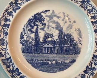 Monticello Blue Transferware Plate — Decorative Monticello blue transferware plate featuring the West Front view of Thomas Jefferson's home. The white ceramic plate has a detailed blue central vignette with a grapevine border and maker stamps on the reverse. Plate is suitable for wall display in the living room; measurements provided below are approximate. Overall condition is good with no visible cracks or large chips; minor surface wear and light crazing consistent with age.