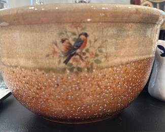 Handmade Glazed Ceramic Mixing Bowl — Large handmade glazed ceramic mixing bowl with textured brown-speckle exterior and a small painted bird motif on one side. Interior shows wheel-thrown concentric rings and a smooth glossy glaze; base is unglazed with kiln-firing coloration. Sturdy, decorative and functional for serving or display; shows light surface wear consistent with use but no chips or cracks visible in photos.