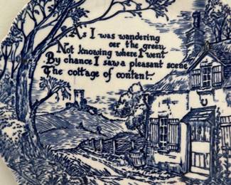 Blue White Staffordshire Plaque — Charming blue-and-white Staffordshire-style ceramic hanging plaque featuring a pastoral cottage scene and poem reading 'I was wandering o'er the green...the cottage of content.' Made in England (mark on back reads Staffordshire - England) with an attached pink hanging cord. Approximately small decorative size suitable for a living room wall or kitchen accent; lightweight and easy to hang. In good condition with visible crazing consistent with age but no visible chips or cracks besides expected surface crazing.