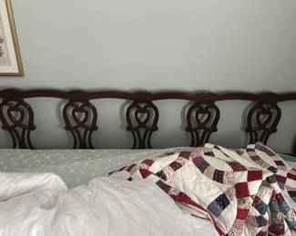 King bed — Solid mahogany headboard with carved pierced splat detailing in a classic heart-shaped motif. The dark wood finish and serpentine top rail complement traditional bedroom sets; pictured mounted behind a mattress in a bathroom for staging. Overall length fits a queen bed; lightweight solid-wood construction makes it easy to move and reattach to a bed frame. Good condition with minor surface wear and small finish scuffs consistent with normal use.