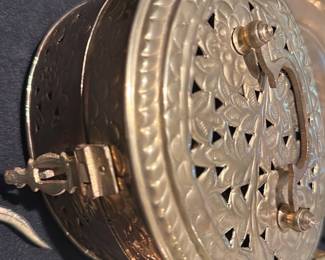 Brass Filigree — Handworked brass filigree incense burner with pierced floral lid and swivel latch. Solid-feeling metal construction with ornate cutwork vents designed for use with charcoal and resin or loose incense; decorative knob handles on the lid and small hinge/latch at the side. Good vintage condition with light surface tarnish and minor surface scratches consistent with age and use; no obvious dents or breaks. Measures compactly and is suitable for mantel or table display as shown.