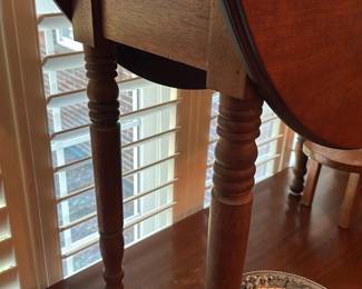 Drop-Leaf Gateleg Side Table — Solid-wood drop-leaf gateleg side table with turned legs and warm medium-brown finish. The hinged drop leaf extends the top for extra surface and folds down neatly when not in use; turned legs and stretcher show traditional country styling. Table shows light surface wear and small scuffs consistent with normal use but appears structurally sound. Handy small dining or lamp table measuring compactly for multipurpose rooms.