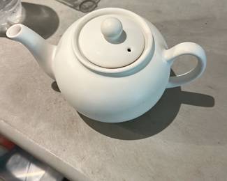 Fiesta White Teapot — Glazed white Fiesta teapot with classic rounded profile and knob lid; mark on the base reads "FIesta" (letters slightly worn) and shows typical Fiesta-style construction. Solid ceramic with a full spout and loop handle, suitable for daily use or display with other Fiesta dinnerware. Surface appears clean with light wear consistent with use but no visible chips or cracks in the photos. Measures small to medium size, ideal for serving 2–4 cups.