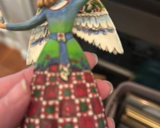 Jim Shore Angel Figurine — Jim Shore hand-painted resin angel figurine with folk-art patterns and a gold halo. The piece shows detailed painted quilting on the skirt, decorative wings, and a small bird in the raised hand; Jim Shore branding is visible on the base. Good display condition with normal light surface wear consistent with gentle use; no obvious chips or cracks visible in photos. Compact decorative accent for mantel, shelf, or holiday display.