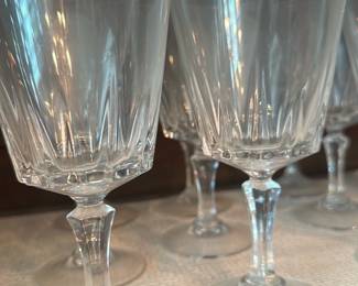 16 Cut Crystal Wine Goblets — Set of clear cut crystal wine goblets with faceted bowl and slender stems, ideal for dining room or entertaining. Each glass features vertical cut lines on the lower bowl and a faceted knop on the stem, crafted in clear lead-style crystal. Measuring approximately 7.5 in tall with a 3.25 in bowl diameter, they are lightweight enough for regular use but substantial in feel. Overall condition is good with no visible chips or cracks noted; minor surface scratch/marks from normal use.
