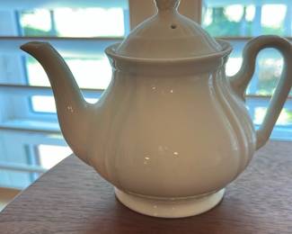 White Porcelain Teapot — Simple white porcelain teapot with a rounded, fluted body, classic curved spout and loop handle. Glazed ceramic shows a clean, glossy finish with no visible chips or cracks in the photos; lid has a finial and a steam hole. Elegant, traditional shape suitable for everyday use or casual table service; measures small to medium (see dimensions). Condition appears good with only light surface wear consistent with normal use.