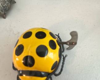 Wind-Up Tin Ladybug Toy — Bright yellow and black wind-up tin ladybug toy with visible key on the back and painted details. Metal body shows light surface wear and a small dent on the shell consistent with age and play; winding key present and appears functional though working condition not fully tested. Compact collectible toy likely mid-20th century style, great for display or toy collectors. Measures small and lightweight—see dimensions below.