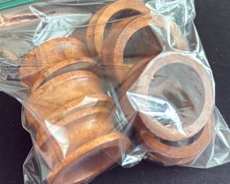 Wooden Napkin Rings Set — Set of six wooden napkin rings with a warm honey-brown finish shown stored together in a resealable bag. Each ring is turned with subtle profile variations and appears to be solid wood with light surface wear and small handling marks consistent with previous use. Practical dining or craft accessory that can be used as-is or refinished to match a table setting; sold as the six-piece set shown.