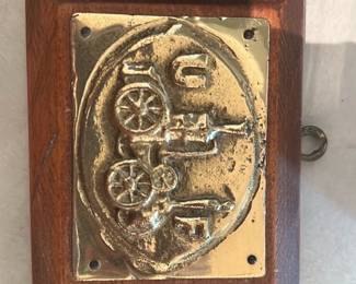 Brass Cannon Relief Plaque Wood — Small wall plaque featuring a raised brass relief of a cannon motif mounted on a stained wood backer. The brass plate is nailed at the corners and shows light surface tarnish and minor scratches consistent with age; the wood backer has a few small dings but remains solid. Simple decorative piece likely mid-century or later, suitable for mantel or wall display as a military or historical accent. See photos for exact condition and hardware.
