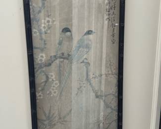 Chinese Bird & Blossom Scroll Print — Delicate Chinese-style vertical print depicting two long-tailed birds perched on a flowering plum branch with calligraphic script at the upper right. Printed on paper and set under glass in a faux bamboo black frame, the piece shows soft muted blues and greys with botanical details including bamboo leaves. Overall framed size approximately 30 x 10 inches, suitable for a sun room or hallway display. Frame and paper show light age-related wear and minor foxing visible through the glass; glass intact and frame structurally sound.