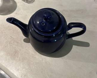 Small Dark Blue Ceramic Teapot — Small dark blue glazed ceramic teapot with lid and integrated spout and handle. Simple rounded form with a glossy finish; lid has a vent hole and knob. Good collectible or everyday use piece — no visible chips or cracks in photos, just light surface wear consistent with normal use. Compact size works well for 1–2 cups of tea.