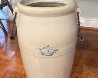 Ceramic Stoneware Crock with Handles — Large glazed ceramic stoneware crock featuring two applied handles with original metal-wire and wooden swing handles and a small blue crown-style cobalt decoration on the body. Thick glazed interior and unglazed rim edge show typical manufacturing marks; photos show a small chip at the rim and light surface wear consistent with age. Sturdy decorative-utility piece good for storage or as a planter; solid, heavy construction and classic farmhouse look.
