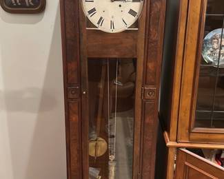 Walnut Longcase Grandfather Clock — Tall walnut longcase (grandfather) clock with carved swan-neck pediment and brass decorative appliqués. The face has Roman numerals with a subsidiary seconds dial and visible pendulum and weight through a front glass panel; the case shows rich figured walnut veneer. Measures approximately 78 inches tall, 20 inches wide and 12 inches deep; good solid piece for a living room or entry. Clock appears to have age-appropriate wear to finish and dial with light surface cracks on the painted face; movement and striking function not verified and may need servicing.